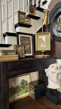 there are many framed pictures on the wall next to a fireplace mantel with a busturine