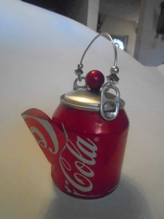 a coca cola can ornament with a cherry on the top, hanging from a hook