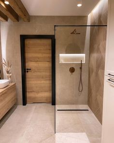 a bathroom with a walk in shower next to a sink and wooden cabinetry on the wall