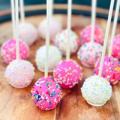 cake pops with sprinkles are arranged on a wooden tray