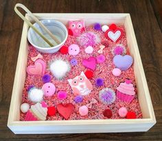 a wooden tray filled with lots of different types of buttons and pins on top of a table