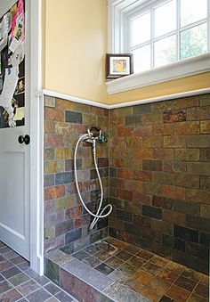 a tiled shower in a bathroom next to a window