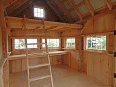 a ladder is in the middle of a room with wooden walls and ceiling, along with windows