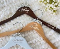 three personalized wooden wedding hangers on a white carpet with flowers in the background