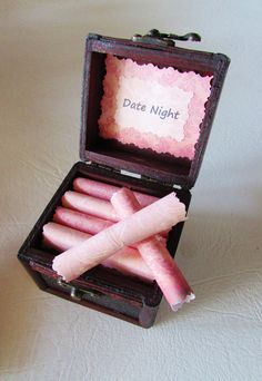 an open box with pink candles inside on a white tableclothed surface and the words date night written in it