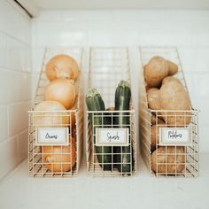 three metal baskets filled with vegetables on top of a white tiled counter next to each other