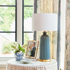 a blue and white vase sitting on top of a table next to a framed photo