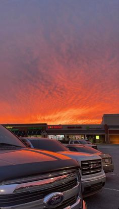 several cars parked in a parking lot at sunset