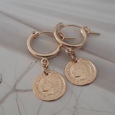 Coin Huggie Hoops Stunning huggie hoop earrings with a  delicate coin charm. The earrings are very lightweight, perfect for every day wear. Material - 14k gold filled Dimensions -  Hoops: app. 1.25 cm / o.5 inches Diameter Charm : app.  1.1 cm / 0.43 inches Diametet. ❤ Thank you for stopping by ❤                                                      Want to see more ?                                                                                                 Back to shop - https://etsy.me/3jk Coin Earrings Gold, Gold Coin Earrings, Matte Gold Earrings, Pineapple Earrings, Skull Pendant Necklace, Gold Pineapple, Hoops Gold, Coin Earrings, Hoop Earrings Gold