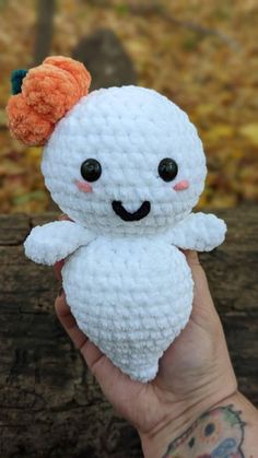 a hand holding a small white crocheted stuffed animal