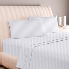 a bed with white sheets and pillows on top of it next to a beige headboard