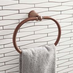 a towel hanging on the side of a brick wall next to a toilet paper roll