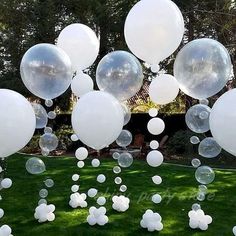 white balloons are floating in the air on green grass