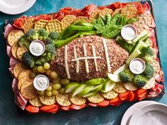 a football shaped platter with cheese, crackers and vegetables