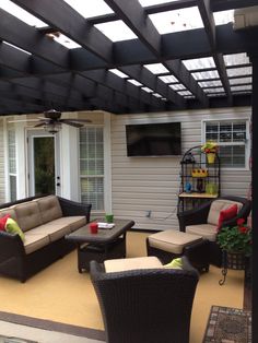 an outdoor living area with couches, chairs and a ceiling fan in the background