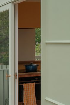 an open door leading to a kitchen with a pot and pan on the stove top