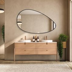 a bathroom with two sinks and a large oval mirror on the wall next to it