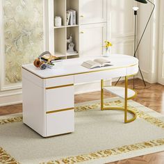 a white desk with gold trim on the top and bottom, sitting in front of a window