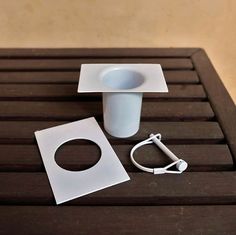 a white vase sitting on top of a wooden table next to an electrical outlet and plug