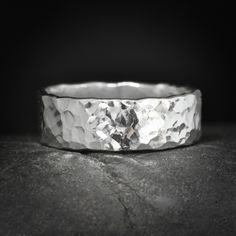 a silver ring sitting on top of a black surface with the background showing it's texture