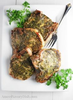 three pieces of meat on a white plate with a fork and parsley next to it