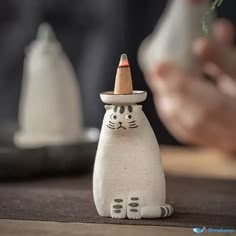 a white cat figurine with a hat on it's head sitting on a table