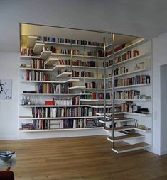 a living room filled with lots of books on top of white shelves next to a wooden floor