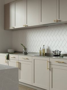 a kitchen with white cabinets and gold handles on the counter tops, along with silver appliances