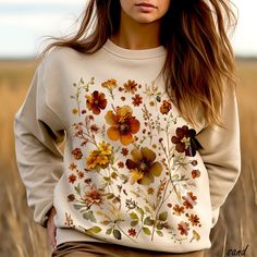 Welcome autumn with open arms while adorned in this captivating botanical sweatshirt that blends fashion and nature seamlessly. Embrace the cozy warmth of the season with intricate autumn flowers, capturing the essence of nature's transition. The stunning cottagecore pressed flowers, each meticulously designed and placed, create a captivating visual narrative of fall's rich palette. Golden yellows, rustic oranges, and deep burgundies intertwine with subtle hints of greens, bringing to life the b Cottagecore Autumn, Visual Narrative, Cottagecore Shirt, Cottagecore Outfits, Autumn Flowers, Nature Shirts, Floral Sweater, Open Arms, Thanksgiving Shirt