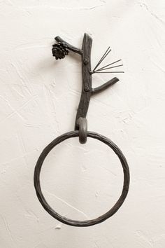 a metal ring with a branch on it hanging from the side of a white wall