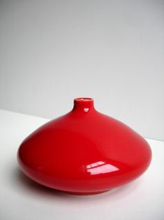 a red vase sitting on top of a white table