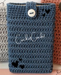 three crocheted pouches with buttons on the front and bottom, one is blue