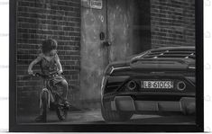 a young boy riding a bike next to a parked car in front of a brick building