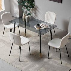 a glass table with four chairs and a plant in the corner next to it on a carpeted floor