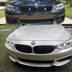 the front end of a silver car parked on top of a grass covered field next to a house