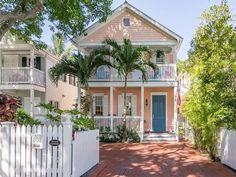 a pink house with white picket fence and palm trees