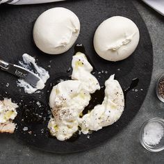 an assortment of food on a black plate next to utensils and spoons