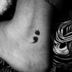 a black and white photo of a person's foot with ink splattered on it