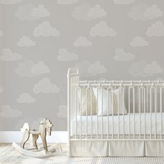 a baby's room with a crib, rocking horse and pink wallpaper