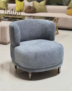 a blue chair sitting on top of a white floor next to couches and pillows