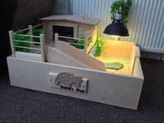 a wooden box with an animal house and stairs in the bottom half, on carpeted floor