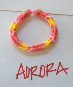 the word aurora written on a piece of paper next to a bracelet with two different colored braids