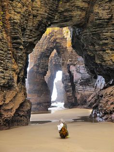 a person walking on the beach in front of an arch shaped rock formation with text that reads, 8 beach of the cathedrals in spain