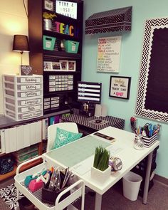 a desk with lots of office supplies on it in a room that has blue walls