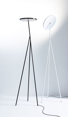 a white floor lamp next to a black tripod light