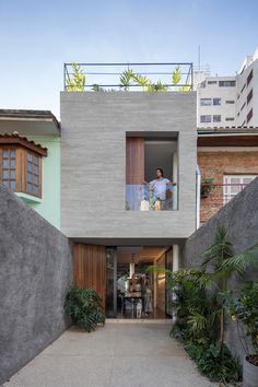 two people standing on the balcony of a modern house with concrete walls and flooring