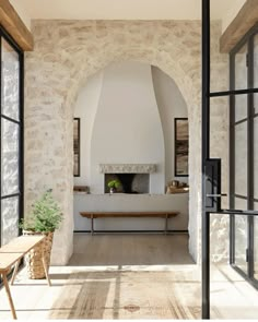 an arched doorway leads into a living room with stone walls and floor to ceiling windows