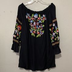 This Elegant And Exquisite Off Shoulder Top By Chelsea & Theodore Has Vibrant Floral Embroidery; A Rounded Neckline That Ties In The Front; And ¾ Length Sleeves With An Elasticized Ruffle At The Bottom. It Is An Absolutely Beautiful Top For Career Or Any Dress Up Occasion. Size Medium Nwt Pit To Pit About 20”Length About 28” Very Stretchy Has 2 Pockets On Side Rayon Black Summer Blouse With Embroidered Sleeves, Black Embroidered Hem Top For Summer, Black Long Sleeve Embroidered Top, Black Long Sleeve Embroidered Top For Summer, Black Embroidered Long Sleeve Top For Summer, Black Embroidered Hem Blouse For Spring, Black Blouse With Embroidered Hem For Spring, Black Long Sleeve Embroidered Top With Floral Print, Black Bohemian Top With Embroidered Sleeves