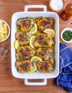 chicken with lemons and herbs in a white dish