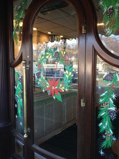 the front door to a store with christmas wreaths and pine cones painted on it